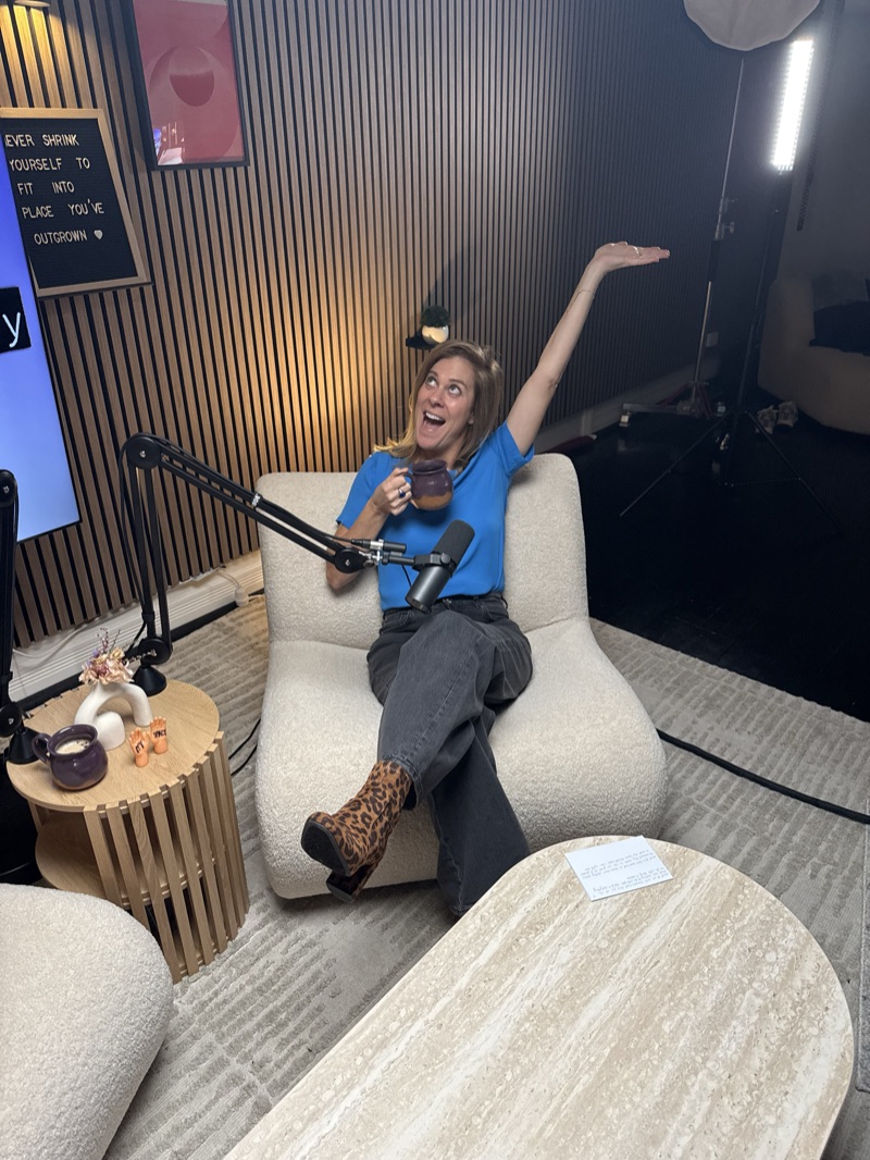 Maddie in the studio, arm thrown up mid-laugh